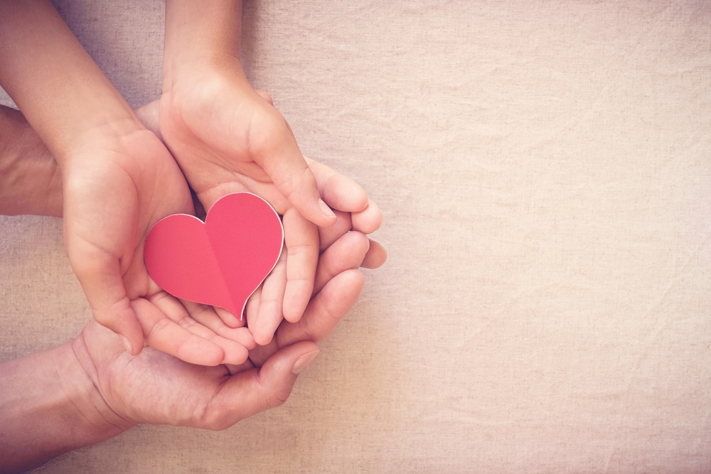 man and woman holding paper heart